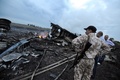ウクライナ東部のシャフチョルスク（Shaktarsk）近くに墜落したマレーシア航空（Malaysia Airlines）機の残骸の近くに立つ人々（2014年7月17日撮影）。(c)AFP/DOMINIQUE FAGET