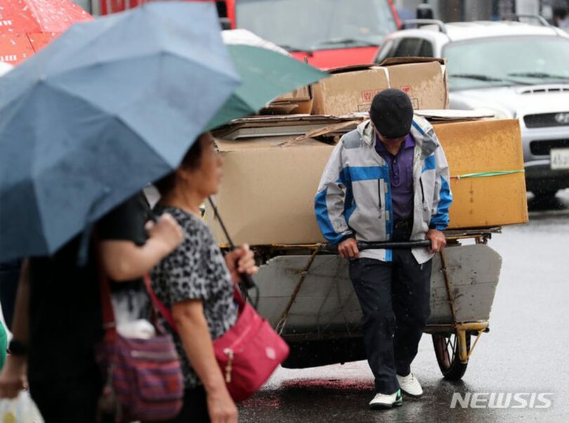 2023年9月13日、ソウル市内の大通りで、古紙を載せたリヤカーを引く高齢者(c)NEWSIS
