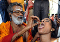 インド・ハイデラバード（Hyderabad）で8日、Bathini Goudさんによる「魚療法（Fish Medicine）」が行われ、投薬を受けるために全国から数千人が集まった。「魚療法」はぜんそくなどの気管支系疾患に効くとして、同国南部に暮らすこの一家が158年前から代々行っている療法で、薬草から作られた秘伝の薬を生きた魚にくわえさせ、順番に患者の口の中に落としていくというもの。投薬は6月のモンスーン到来とともに訪れる縁起の良い日「Mrigasira Karti」に行われる。写真は、子どもに投薬するBathini Goudさん（左、2009年6月8日撮影）。(c)AFP/Noah SEELAM