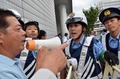 横浜市で開かれた安全保障関連法案に関する地方公聴会の会場前で、警察官を前に拡声器を持って同法案に抗議する男性（左、2015年9月16日撮影）。(c)AFP/Yoshikazu TSUNO
