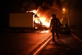 仏西部ナントで、炎上するトラックのそばを歩く警察官（2023年7月1日撮影）。(c)Sebastien SALOM-GOMIS / AFP