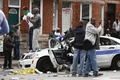 暴動が起きた米メリーランド州ボルティモアで、破壊された警察車両の上に立つ人々（2015年4月27日撮影）。(c)AFP/Getty Images/Drew Angerer