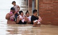 スペイン南東部アルモラディで、子どもを抱えて冠水した道路を歩く人々（2019年9月13日撮影）。(c)JOSE JORDAN / AFP