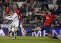 サッカースペイン国王杯（Copa del Rey 2013-14）5回戦、レアル・マドリード（Real Madrid）対オサスナ（CA Osasuna）第1戦。オサスナのアレハンドロ・アリバス（Alejandro Arribas、右）のマークを受けながらボールを送り出すレアル・マドリードのルカ・モドリッチ（Luka Modric、左手前、2014年1月9日撮影）。(c)AFP/DANI POZO