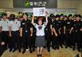 韓国ソウル（Seoul）の金浦空港（Gimpo airport）で、自民党の新藤義孝（Yoshitaka Shindo）衆院議員、稲田朋美（Tomomi Inada）衆院議員、佐藤正久（Masahisa Sato）参院議員らの写真を掲げて3人の鬱陵島訪問計画に抗議する女性（2011年8月1日撮影）。(c)AFP/JUNG YEON-JE
