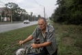 自転車を押して自宅へ帰る男性。ウクライナ東部ドネツク州クラマトルスクで（2022年8月4日撮影）。(c)Bulent KILIC / AFP