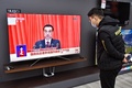 中国全国人民代表大会（全人代）で演説する李克強首相とその映像を見る男性。山東省煙台で（2021年3月5日撮影）。(c)STR / AFP