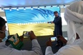 ドバイ万博のウクライナ館で、「#StandWithUkraine（ウクライナと共に）」と表示されたスクリーンの前で写真を撮る人々。アラブ首長国連邦（UAE）ドバイで（2022年2月27日撮影）。(c)Giuseppe CACACE / AFP