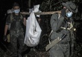 マレーシア北部ペルリス州でみつかった集団埋葬地から、遺体を収容する警察官ら（2015年5月28日撮影）。(c)AFP/MOHD RASFAN