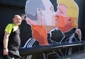 リトアニアの首都ビリニュスで、キスをするドナルド・トランプ氏とウラジーミル・プーチン大統領が描かれた壁画のそばでポーズを取る飲食店主のドミニカス・チェチュカウスカスさん（2016年5月13日撮影）。(c)AFP/Petras Malukas