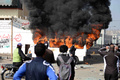 エジプト北部ポートサイド（Port Said）で昨年2月に発生したサッカー場での暴動事件の裁判で被告21人に死刑判決が下されたことを受け、住民と警察の間で衝突が発生、放火された衛星放送局の車と立ち上る煙（2013年1月26日撮影）。(c)AFP