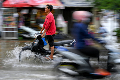 【今日の1枚】水しぶきもへっちゃら？ 冠水した通りを進む二輪車、カンボジア