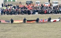 フランス・ルベルネで行われたドイツ格安航空会社ジャーマンウイングス4U9525便墜落の犠牲者追悼集会で、石碑（中央）の周りに集まる遺族と、犠牲者の出身国の国旗を掲げる救助隊（手前、2015年3月26日撮影）。(c)AFP/PASCAL GUYOT