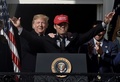 「アメリカを再び偉大に」と書かれた赤い帽子をかぶってスピーチするワシントン・ナショナルズのカート・スズキ（中央）の肩に手をやるドナルド・トランプ大統領（左、2019年11月4日撮影）。(c)Olivier Douliery / AFP