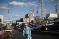 福島第一原子力発電所の2号機原子炉（左奥）と3号機原子炉（中央）付近を歩く東京電力の従業員（2018年1月31日撮影）。(c)AFP PHOTO / Behrouz MEHRI