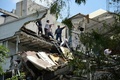 メキシコの首都メキシコ市で、地震により損壊した建物の上に立つ人々（2017年9月19日撮影）。(c)AFP/Ronaldo SCHEMIDT