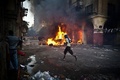 エジプト・カイロ（Cairo）のラムセス広場（Ramses Square）近くで、治安部隊との衝突のさなか炎を上げる車の前を走り抜けるムスリム同胞団支持者（2013年8月16日撮影）。(c)AFP/VIRGINIE NGUYEN HOANG