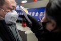 中国・北京の地下鉄駅の入り口で乗客男性の体温を測る係員（2020年1月24日撮影）。(c)NICOLAS ASFOURI / AFP