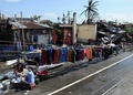 台風30号が通過したフィリピン東部レイテ（Leyte）州タクロバン（Tacloban）で、道路脇に洗濯物を干す女性（2013年11月10日撮影）。(c)AFP/TED ALJIBE