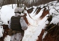 ウクライナ東部ドネツク州アウディーウカ付近の親ロシア分離独立派との前線で、雪に覆われた塹壕を歩くウクライナの兵士（2022年2月2日撮影）。(c)Anatolii STEPANOV / AFP