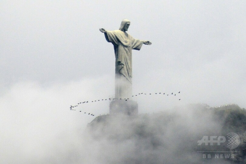 雲がかるリオのキリスト像と鳥の群れ、ブラジル