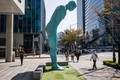 韓国ソウルで、彫刻家のユ・ヨンホさんの作品「グリーティング・マン」の前を歩く通行人（2022年4月8日撮影）。(c)Anthony WALLACE / AFP
