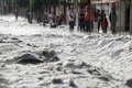 メキシコ・ハリスコ州グアダラハラ東部で、ひょうに覆われた道路脇の歩道にとどまる人々（2019年6月30日撮影）。(c)ULISES RUIZ / AFP