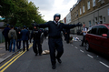 英ロンドン（London）北部のトッテナム（Tottenham）で若者が警官に射殺された事件をきっかけに6日に発生した暴動は、8日夜から9日未明にかけて市内および郊外各地に広がり、ロンドンは混乱の様相を呈している。さらに暴動は、中部バーミンガム（Birmingham）やリバプール（Liverpool）にも飛び火。デービッド･キャメロン（David Cameron）は非常事態に対処するため、伊トスカーナ（Tuscany）での休暇を切り上げ、英国に向かっている。

　ロンドンとその郊外では南部クロイドン（Croydon）、ペッカム（Peckham）、ルイシャム（Lewisham）、クラパム（Clapham）、東部ハックニー（Hackney）、北部カムデン（Camden）、西部イーリング（Ealing）などで、若者らが路上に繰り出し、建物への放火や店舗の略奪を行っており、機動隊が収拾にあたっているが、各地で放火による火の手があがっている。

　一方、バーミンガムでも8日未明、市内中心部で若者らが店舗の窓ガラスを割ったり略奪するなどして87人が逮捕された。また同市の警察署が放火で炎上したという。リバプールでも駐車車両が放火され、同市警察は「路上における、いかなる暴力行為も容認できない」との声明を出し、暴動に厳しく臨む姿勢をみせている。

写真はハックニーで、報道陣に下がるよう命じる警察官（2011年8月8日撮影）。(c)AFP/ LEON NEAL