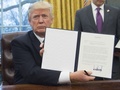 ホワイトハウスの大統領執務室で、署名したTPP離脱に関する大統領令を掲げるドナルド・トランプ大統領（2017年1月23日撮影）。(c)AFP/SAUL LOEB