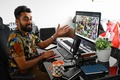 米国人アーティスト、ビープルのデジタルコラージュ作品（画面内）を非代替性トークン（NFT）として6930万ドル（約75億円）で落札したビグネシュ・スンダレサン氏（2021年4月7日撮影）。(c)Roslan RAHMAN / AFP