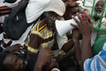 ハイチの首都ポルトープランス（Port-au-Prince）で、崩壊した大統領官邸のフェンスの内側から集まった市民と語るルネ・プレバル（Rene Preval）ハイチ大統領（右奥、2010年1月30日撮影）。(c)AFP/JEAN-PHILIPPE KSIAZEK