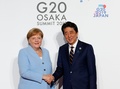 大阪で開催中の20か国・地域（G20）首脳会議の歓迎行事で、アンゲラ・メルケル独首相（左）を迎える安倍晋三首相（右、2019年6月28日撮影）。(c)KIM KYUNG-HOON / POOL / AFP