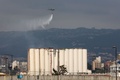 レバノンの首都ベイルート港湾地区で、一部が倒壊した穀物サイロの上空から消火剤をまく軍のヘリコプター（2022年7月31日撮影）。(c)Anwar AMRO / AFP