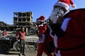 シリア北部ラッカで、破壊された建物の横を通り過ぎるサンタクロースの格好をした男性ら（右）と、それを眺める子どもたち（2017年12月26日撮影）。(c)AFP PHOTO / Delil souleiman