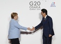 大阪で開催中の20か国・地域（G20）首脳会議の歓迎行事で、アンゲラ・メルケル独首相（左）を迎える安倍晋三首相（右、2019年6月28日撮影）。(c)KIM KYUNG-HOON / various sources / AFP