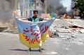 エジプト・カイロ（Cairo）で軍に解任されたムハンマド・モルシ（Mohamed Morsi）前大統領の支持者らが続けていた座り込みの抗議デモは14日、治安部隊が強制排除に乗り出し、多数の死者を出す流血の惨事となった。エジプト各地でもムスリム同胞団（Muslim Brotherhood）と治安部隊が衝突。エジプト保健省は15日、全国で少なくとも464人が死亡したと発表した。うち421人が民間人という。

治安部隊はモルシ氏支持派が座り込みを続けていたカイロ東部のラバ・アルアダウィヤ（Rabaa al-Adawiya）モスク近くの広場と、中心部のナハダ（Nahda）広場の2か所に、夜明けとともにブルドーザーを従えて突入。軍はかねて、座り込みを止めなければ強制的に排除すると警告していた。保健省によると、各地の死者数はラバ・アルアダウィヤモスク付近で137人、ナハダ広場では57人、その他全国各地で227人となっている。

写真は北部の沿岸都市アレキサンドリア（Alexandria）で、「アレキサンドリアはクーデターに反対する」と書かれた旗を手にする同胞団の支持者（2013年8月14日撮影）。(c)AFP