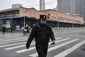 中国・武漢で、新型コロナウイルスが検出された海鮮市場前を歩く警察官（2020年1月24日撮影）。(c)Hector RETAMAL / AFP