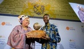 オランダ・ハーグで開かれた「国際子ども平和賞」の授賞式で、2011年のノーベル平和賞を受賞したリベリアの平和活動家リーマ・ボウイー氏（左）から像を手渡されるリベリアのエイブラハム・ケイタさん。（2015年11月9日撮影）。(c)AFP/ANP/BART MAAT
