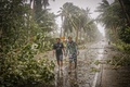 フィリピン中部の東サマル州で、台風1号の強風と豪雨の中、なぎ倒された木が横たわる幹線道路を歩く人々（2020年5月14日撮影）。(c)Alren BERONIO / AFP