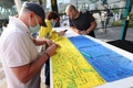 ドバイ万博のウクライナ館で、ウクライナ国旗にメッセージを書き込む来場者。アラブ首長国連邦（UAE）ドバイで（2022年2月27日撮影）。(c)Giuseppe CACACE / AFP