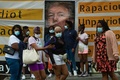米首都ワシントンのホワイトハウスの近くで、ドナルド・トランプ大統領の写真があしらわれた横断幕の前を歩く人々（2020年6月27日撮影）。(c)Roberto SCHMIDT / AFP