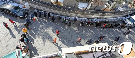 タプコル公園近くの無料給食所で昼食を受け取るために並ぶお年寄りら(c)news1