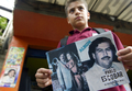 コロンビア・メデジン（Medellin）の貧困地区で、麻薬王パブロ・エスコバル（Pablo Escobar）のシールブックを手にする少年（2012年8月8日撮影）。(c)AFP/Raul ARBOLEDA