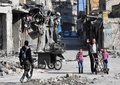 シリア北部アレッポ旧市街で、新たに奪還した地域を巡回する政府軍側の戦闘員に手を振る男性（2016年12月8日撮影）。(c)AFP/GEORGE OURFALIAN