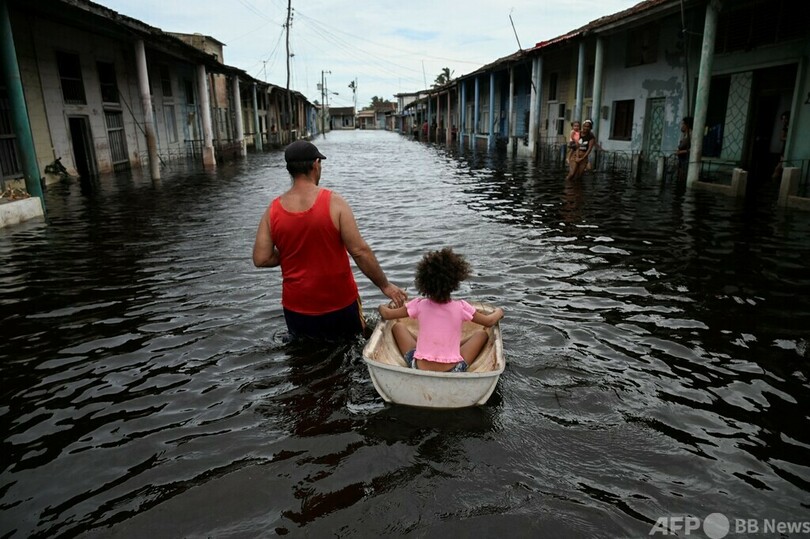 【今日の1枚】ハリケーン一過、冠水した通りを浮き具で移動する男性 キューバ