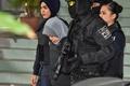 マレーシア首都クアラルンプール郊外のシャーアラム高等裁判所での公判後、警察に付き添われ裁判所を後にするインドネシア国籍のシティ・アイシャ被告（中央、2018年6月27日撮影）。(c)AFP/Mohd RASFAN