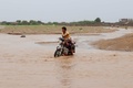 イエメン・ホデイダ州コーハ地区で、冠水した場所をバイクで通る人（2024年9月1日撮影）。(c)Khaled ZIAD / AFP