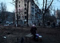 ウクライナの首都キーウで、ロシアの攻撃で損壊した集合住宅の近くで携帯電話をかける住人（2022年12月31日撮影）。(c)SERGEI CHUZAVKOV / AFP