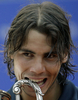 男子テニス、バルセロナ・オープン・バンコ・サバデル（%%Barcelona Open Banco Sabadell 2009%%）シングルス決勝。大会第1シードのラファエル・ナダル（%%Rafael Nadal%%、スペイン）は、大会第4シードのダビド・フェレール（%%David Ferrer%%、スペイン）と対戦。ナダルはセットカウント2-0（6-2、7-5）のストレートで勝利し、大会5連覇を達成した。写真は優勝を果たし、トロフィーをかむラファエル・ナダル。（2009年4月26日撮影）(c)AFP/JOSEP LAGO