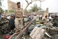 車両を使った自爆攻撃を受けたイラクの首都バグダッド（Baghdad）市行政庁舎前で、倒れた鉄塔の上に乗る警備員（2009年10月25日撮影）。(c)AFP/AHMAD AL-RUBAYE